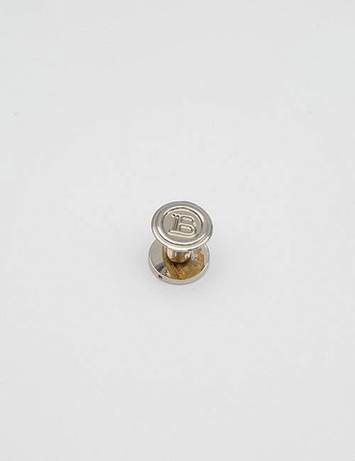 The YIPAI Adornments is a small silver pin featuring a flat, round top engraved with the letter B, displayed on a plain white background.