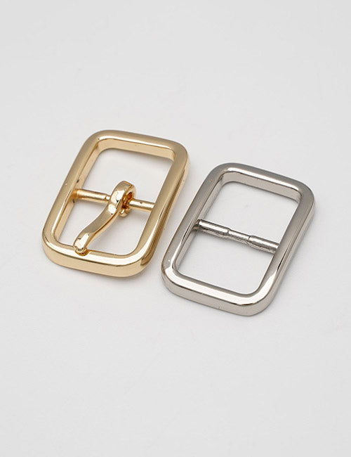 Two YIPAI Buckles are displayed on a light gray surface: one gold with a central prong and one silver without. Both have rectangular shapes, rounded edges, and a smooth finish.