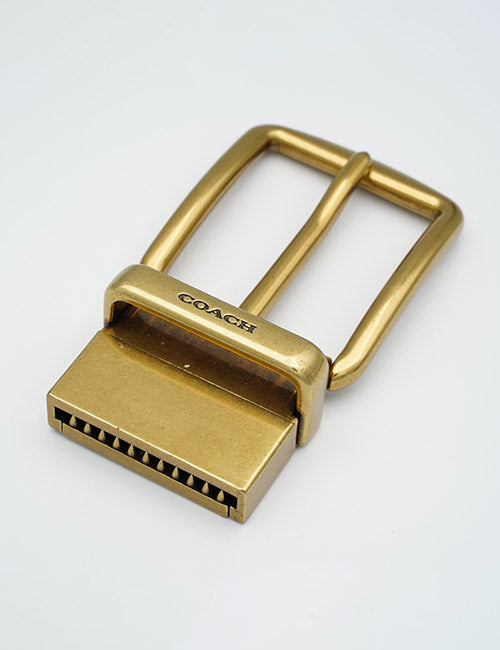 A gold-colored YIPAI Buckles metal belt buckle with YIPAI engraved, featuring a unique rectangular end with several small teeth, photographed on a plain white background.