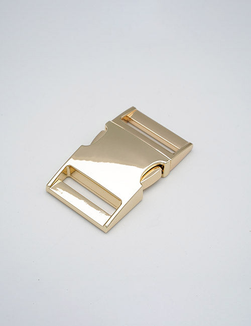 A YIPAI Buckles shiny gold metal side-release buckle, rectangular with smooth edges and two strap slots, rests on a plain light gray background.