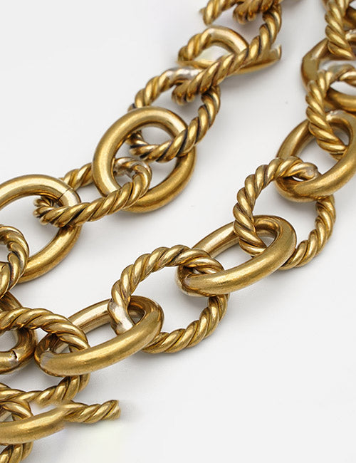 Close-up of YIPAI Chains, featuring alternating smooth and twisted oval gold links, arranged diagonally on a white background.