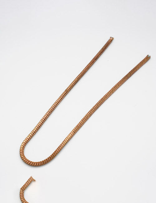 The YIPAI Chains necklace features a gold-toned, flat, and slightly curved herringbone design with a ribbed texture. Displayed in a gentle U-shape on a white background.