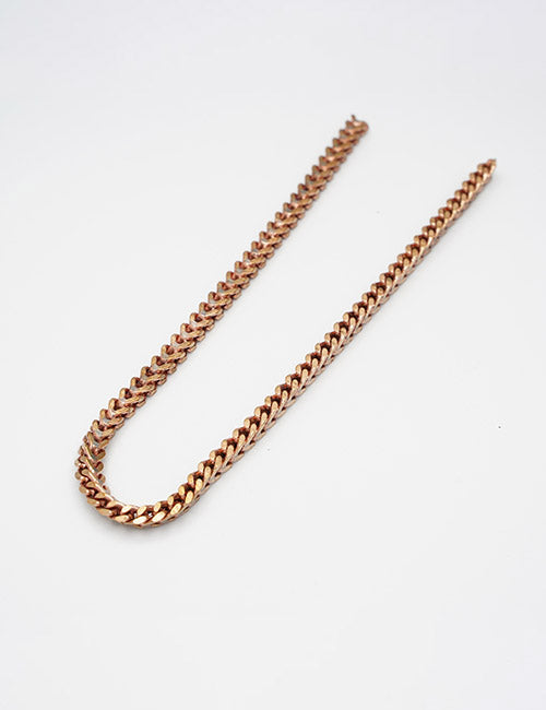A gold-colored flat curb chain necklace from YIPAIs Chains collection is displayed in a gentle U-shape on a plain white background.
