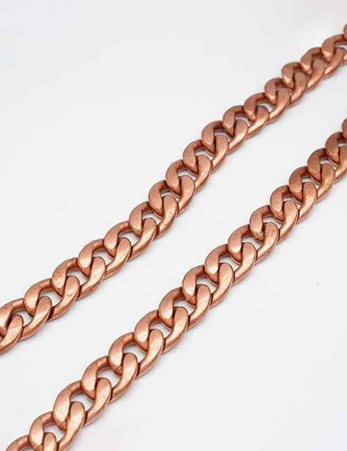 Two thick, copper-colored Chains by YIPAI are laid parallel on a white surface. They feature large, flat, interlocking links for a bold and sturdy look.