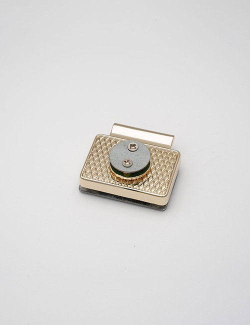 A small, rectangular, gold-colored YIPAI Closures with a textured crisscross design and a central silver disc secured by two screws, displayed on a plain white background.
