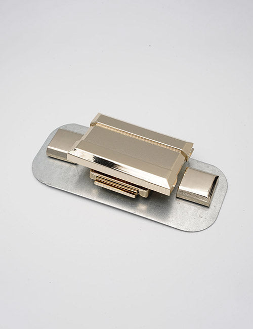 A gold, rectangular metal clasp from YIPAI Closures with geometric edges is mounted on a thin, oval silver base against a plain white background.