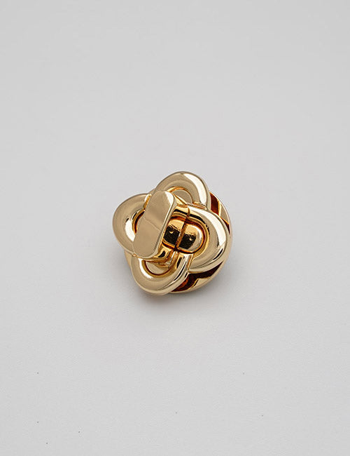 A shiny, gold-toned metal brooch from YIPAI called Closures, featuring an interlocked knot design, displayed against a plain light gray background.