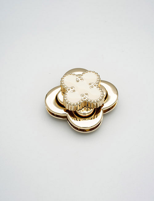 The YIPAI Closures is a gold and white flower-shaped decorative object with layered petals and a glossy finish, shown on a plain light background.