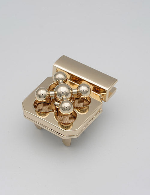 The YIPAI Closures features a shiny gold finish, six spherical knobs on top, a hexagonal base with four short legs, and an open hinged lid at the back, shown against a plain light background.