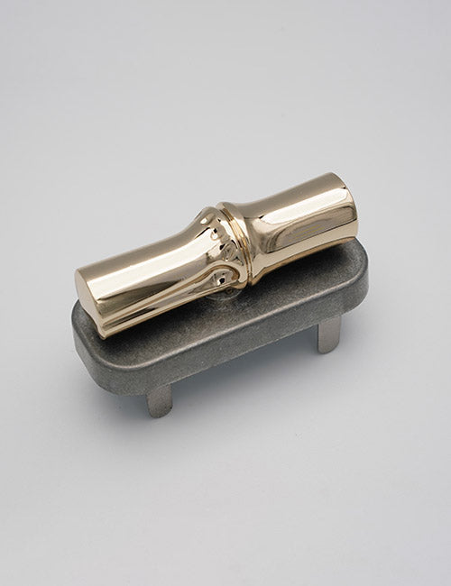 A YIPAI Closures shiny brass saxophone mouthpiece sits on a gray rectangular stand with two short legs, set against a plain light background.