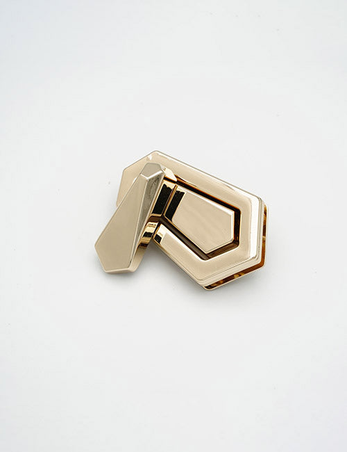 The YIPAI Closures is a geometric, gold-colored metal object with angular shapes and a hinge, displayed against a plain white background.
