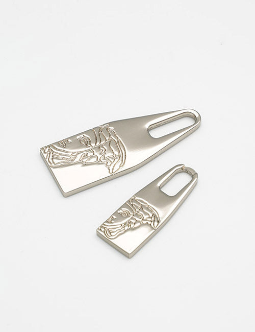 Two YIPAI Fasteners metallic zipper pulls, featuring embossed classical face designs in large and small sizes, displayed on a plain white background.