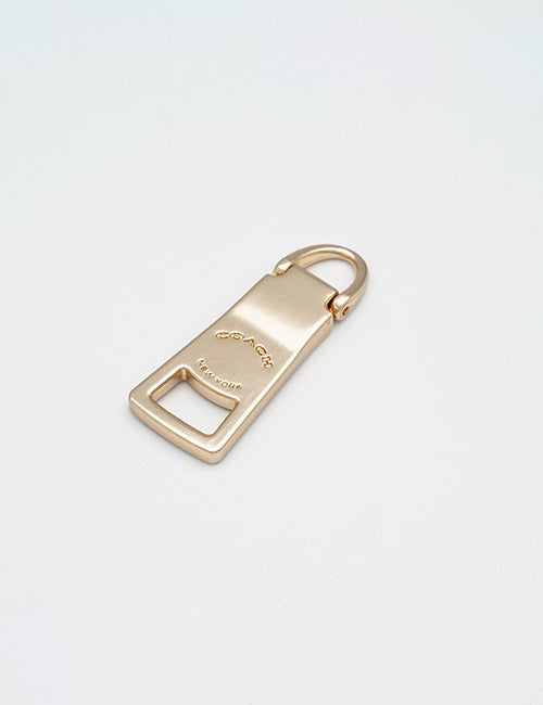 A gold-toned metal keychain from YIPAI called Fasteners, featuring a flat rectangular body with the logo and a small ring at the top for attaching to keys.