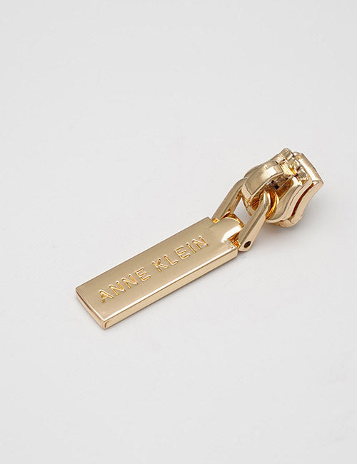 A close-up of a gold zipper pull with YIPAI engraved on the rectangular tab, from their Fasteners line, placed against a plain white background.