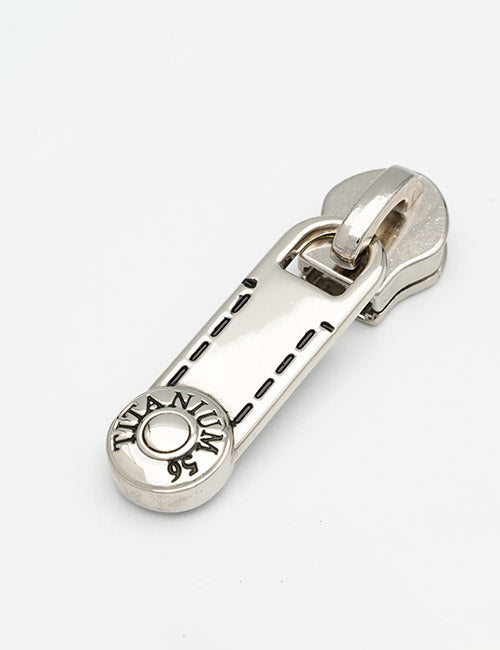 A close-up of a shiny silver YIPAI Fasteners zipper pull, engraved with TITANIUM 95 in black around a small circular end, photographed against a plain white background.