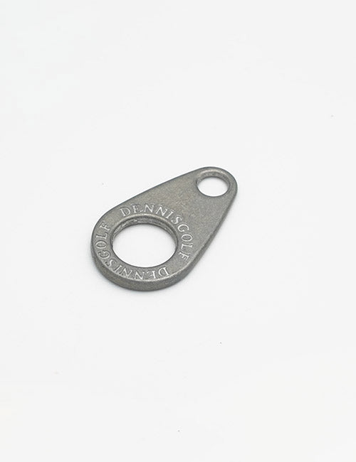 A small, oval metallic YIPAI Fastener with a large center hole and a smaller hole near the tip is shown on a plain white background. DENNISGOLF is engraved along the edge.