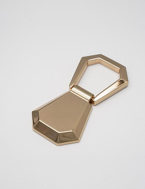 The YIPAI Handles keychain features a geometric, gold-colored hexagonal loop attached to a faceted polygonal pendant, set against a plain light background.