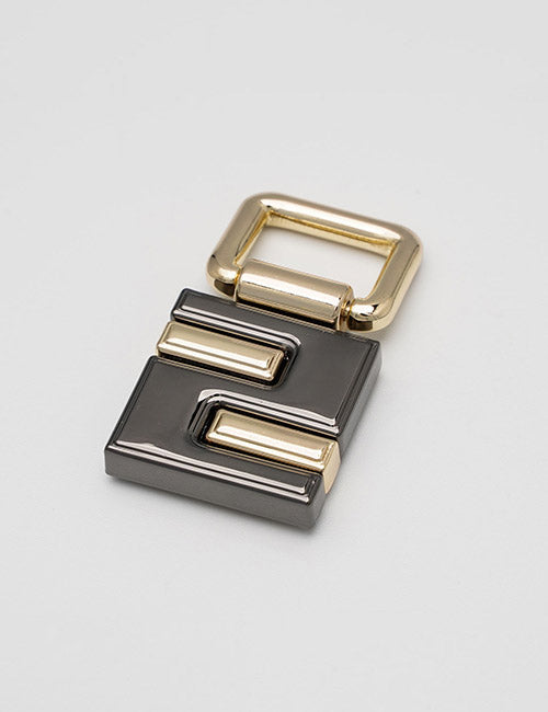 The YIPAI Handles keychain is a metallic, rectangular accessory with a gold and black geometric pattern and a large gold loop on top, shown against a plain light gray background.