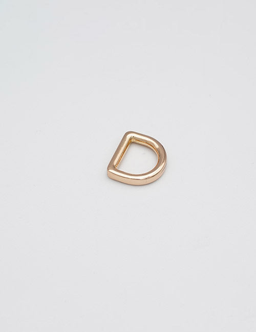 A small YIPAI Rings & Slides gold-colored metal D-ring lies flat on a plain white background.