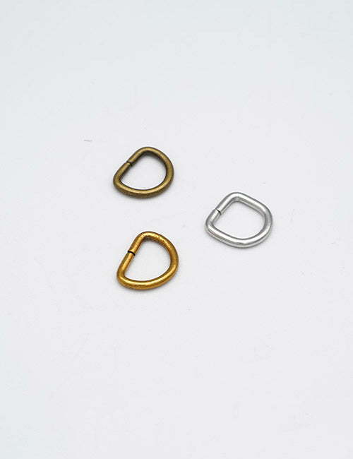 Three metal buckles from YIPAI Rings & Slides—one gold, one brass, and one silver D-ring—are arranged in a triangle on a plain white background.