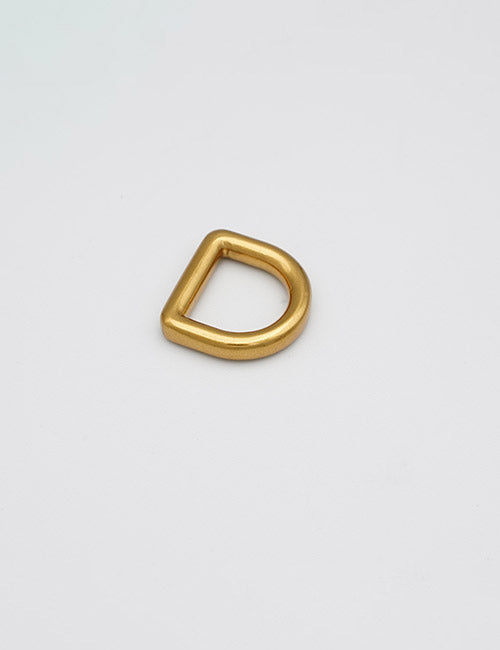 A single YIPAI Rings & Slides gold metal D-ring rests on a plain white surface.
