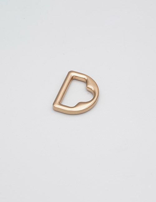 A single gold D-ring from YIPAI’s Rings & Slides lies flat on a plain, light gray background.