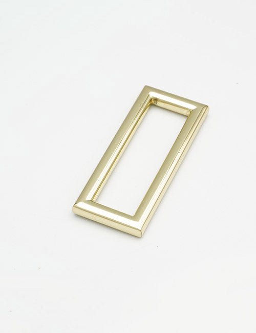 A shiny, rectangular gold-colored metal YIPAI Rings & Slides frame with smooth, rounded edges lies flat on a white surface; its center is hollow.