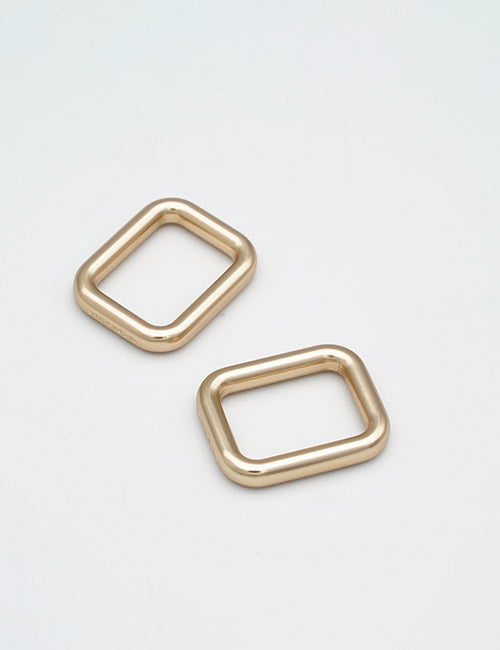 Two rectangular, gold-colored metal Rings & Slides by YIPAI with rounded edges are placed at slight angles to each other on a plain white surface.