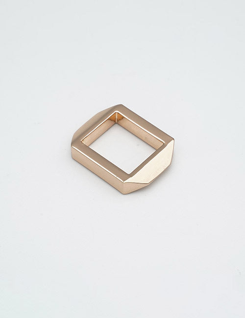 A square-shaped, gold-colored metal ring with beveled edges from YIPAIs Rings & Slides collection rests on a plain, light gray surface.