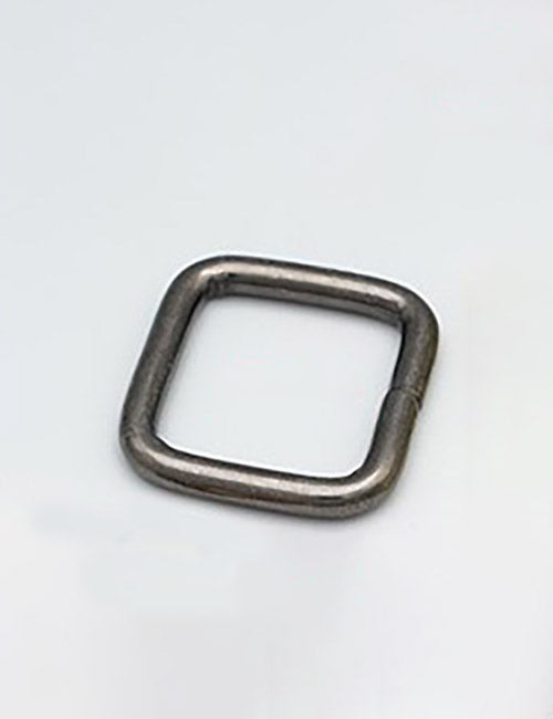 A metallic, square-shaped YIPAI Rings & Slides ring with rounded edges rests on a plain, light gray surface.