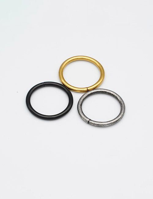 Three minimalist metal rings—gold, black, and silver—from YIPAI’s Rings &Slides collection are arranged in a triangle on a plain white background.