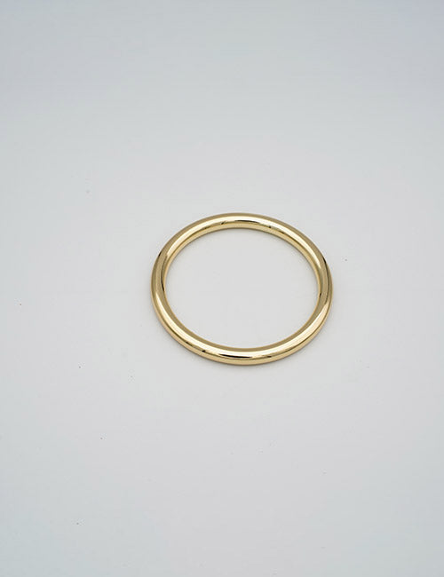 A sleek gold bangle bracelet from YIPAIs Rings &Slides collection is displayed against a plain light gray background.