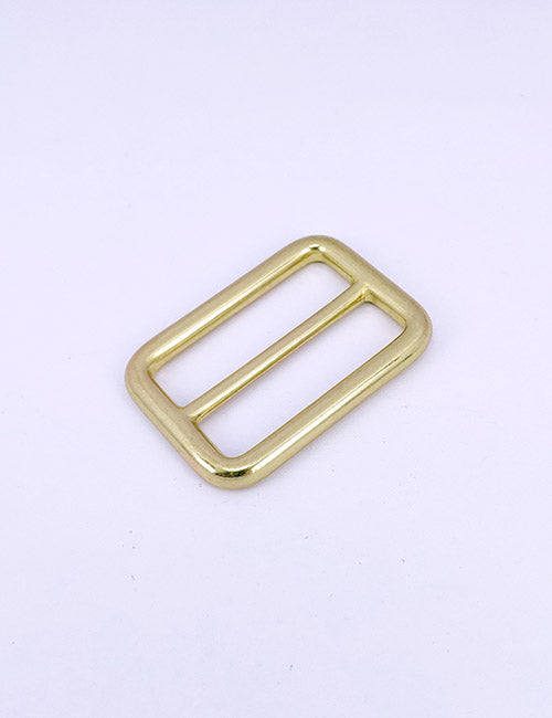 A YIPAI Rings & Slides rectangular brass buckle with rounded edges is displayed on a plain white background.