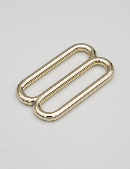 Two shiny, elongated oval-shaped gold metal Rings & Slides by YIPAI are placed side by side on a plain light gray background.