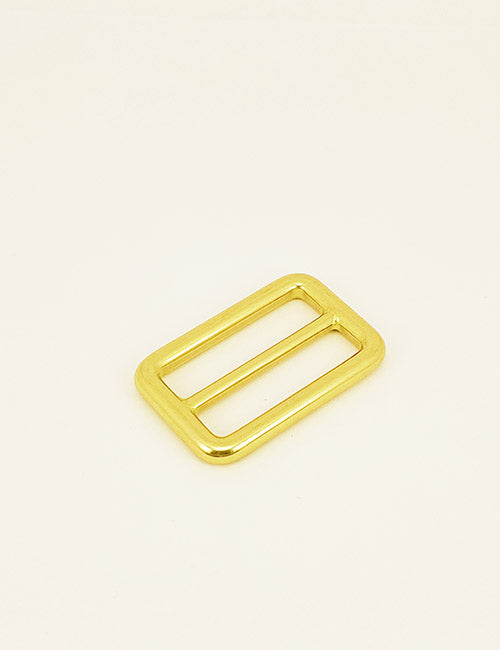 A gold rectangular metal slider buckle from YIPAIs Rings & Slides collection featuring two parallel bars, displayed on a simple light background.