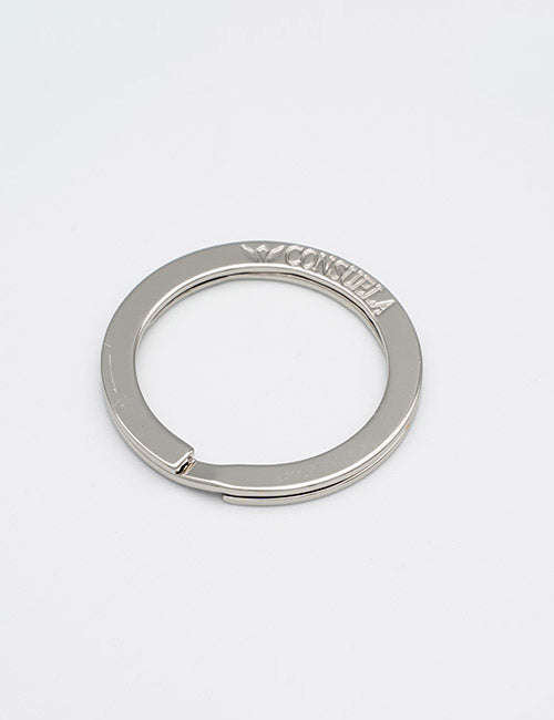 A silver metal key ring from YIPAIs Rings &Slides collection, shaped like a flat circle with a small opening and CONSUELEA engraved on the top side.