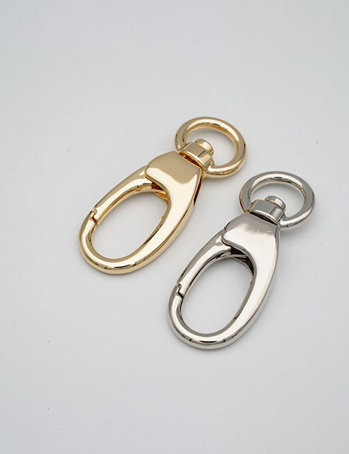 Two YIPAI Snap Hooks, one gold and one silver, are placed side by side on a plain light grey background. Each Snap Hook features a round keyring attached at the top.