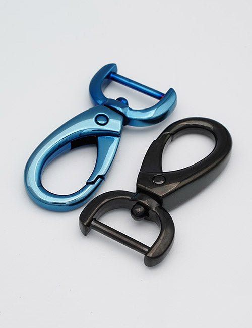 Two YIPAI Snap Hooks, one blue and one black, with a curved design and spring-loaded clasp, are lying on a white surface.